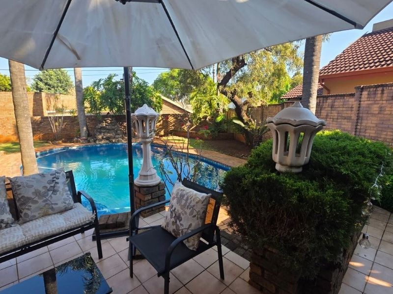 Outdoor entertainment area featuring a swimming pool, tiled patio space, and brick boundary walls in a private garden setting.