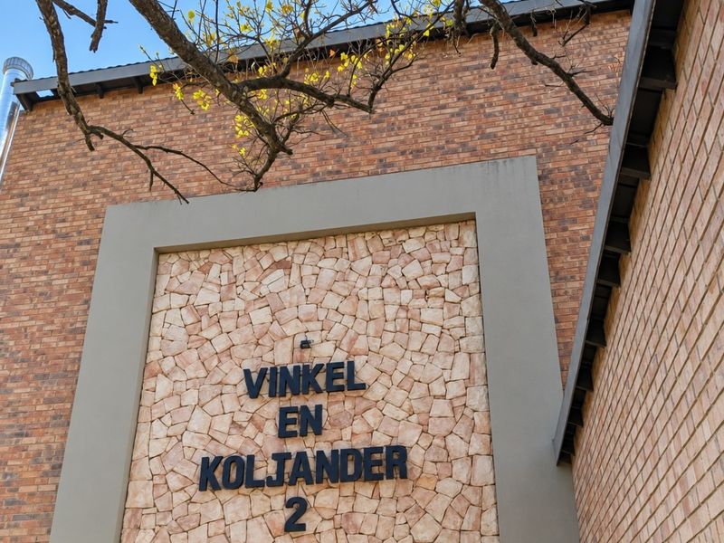 A modern exterior facade featuring a combination of face brick and decorative stone cladding with prominent building signage.