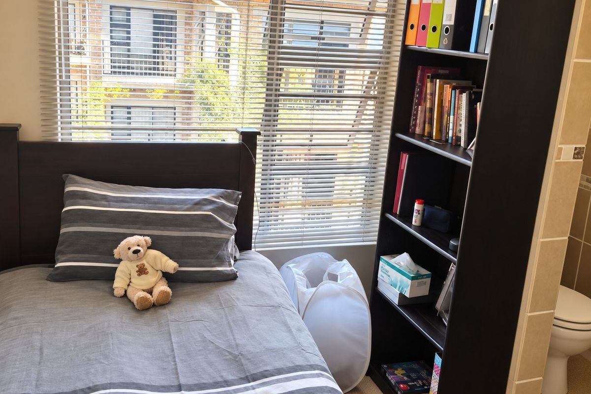 A bedroom featuring venetian blinds and an adjacent bathroom area with a visible toilet.