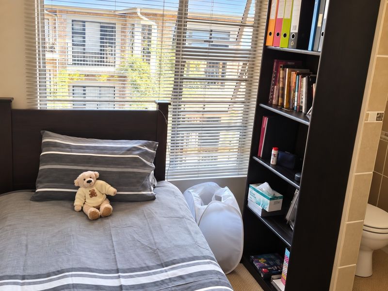 A bedroom featuring venetian blinds and an adjacent bathroom area with a visible toilet.