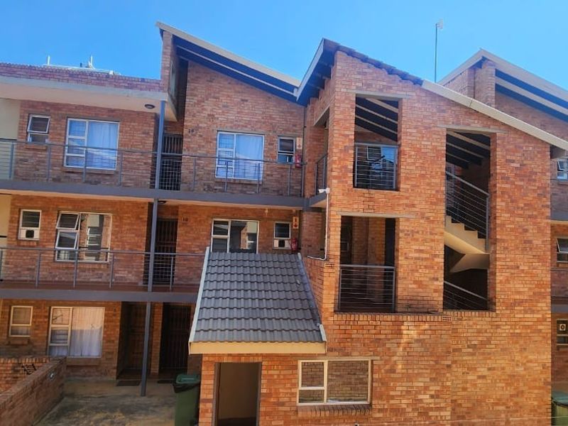 A multi-story residential building featuring a face brick facade, metal balustrades, and external stairwell access.
