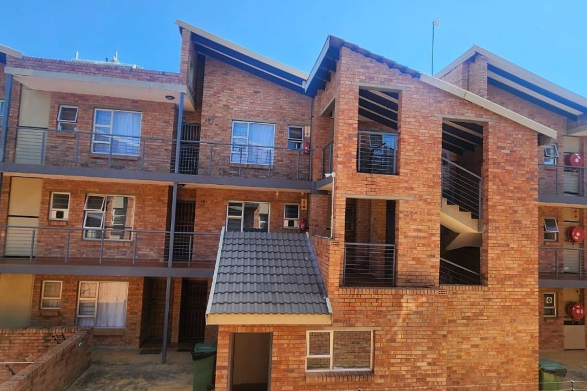 A multi-story residential building featuring a face brick facade, metal balustrades, and external stairwell access.