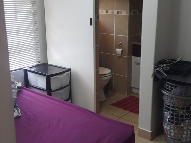 Bedroom featuring tiled flooring, venetian blinds, and a sliding door providing access to an en-suite bathroom.