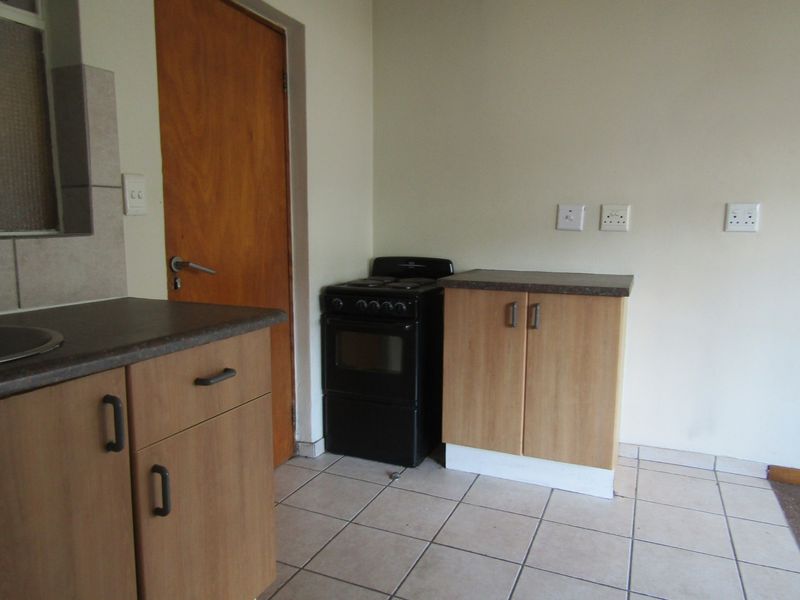 A functional kitchen area featuring laminate cabinetry, a freestanding stove, and ceramic floor tiles, offering a clean and practical space for culinary activities.
