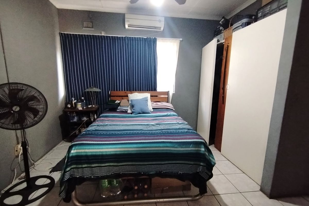 A functional bedroom featuring tiled flooring, a built-in wardrobe, and an air conditioning unit for climate control.