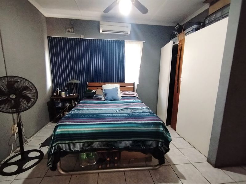 A functional bedroom featuring tiled flooring, a built-in wardrobe, and an air conditioning unit for climate control.