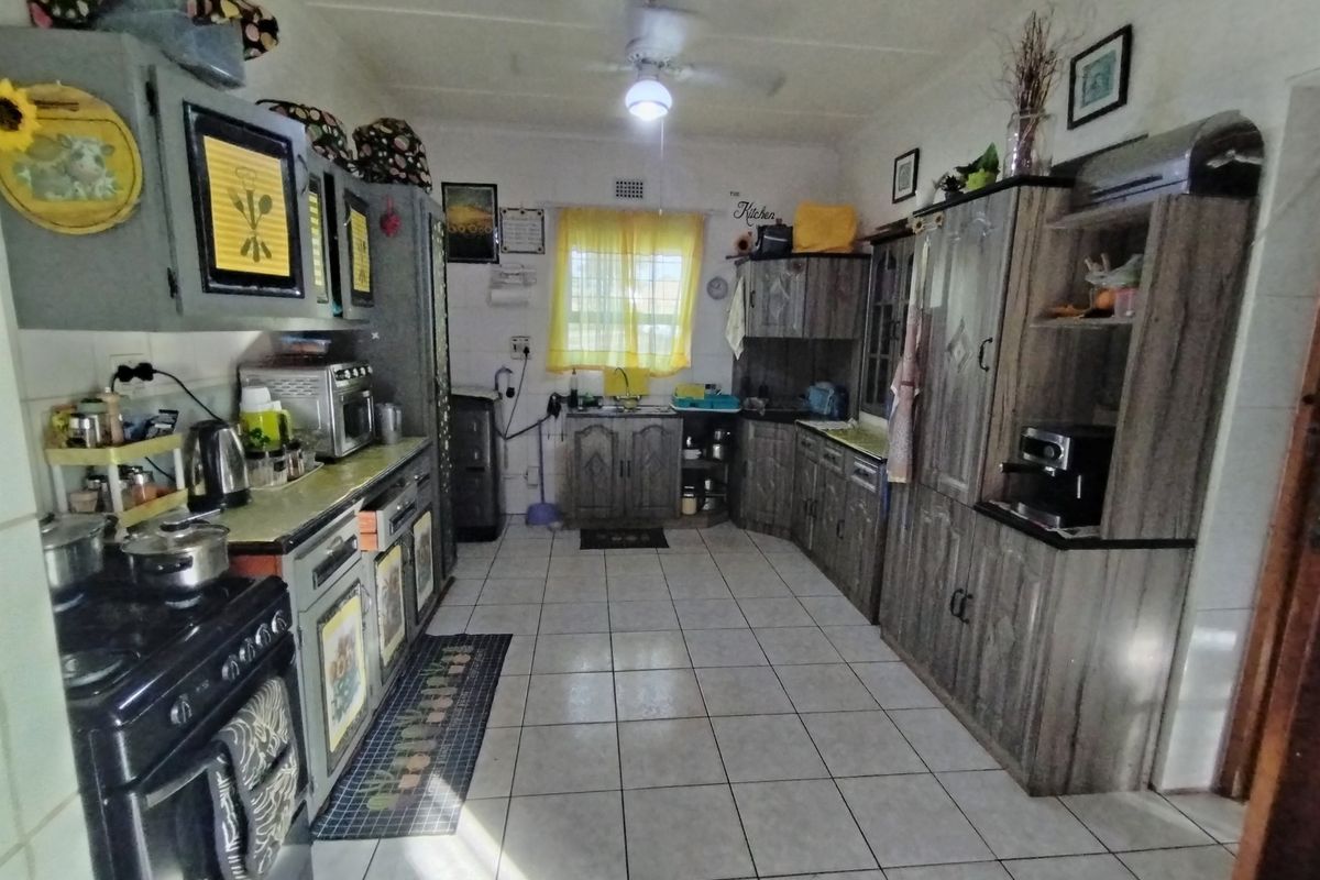 A functional kitchen featuring tiled flooring, extensive built-in cabinetry, and a ceiling fan, offering a practical layout with potential for modern updates.