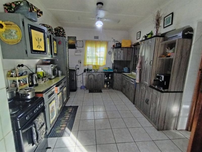 A functional kitchen featuring tiled flooring, extensive built-in cabinetry, and a ceiling fan, offering a practical layout with potential for modern updates.