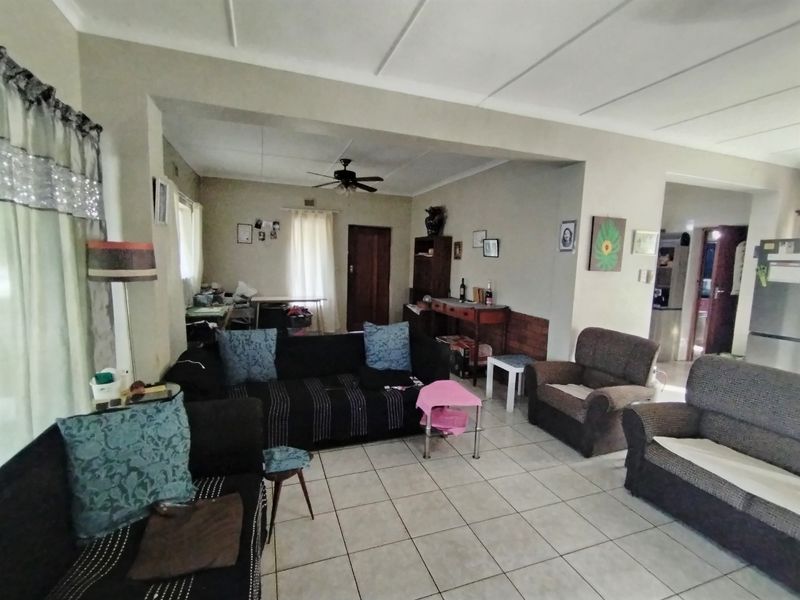 Spacious open-plan living area featuring tiled flooring, a ceiling fan, and neutral wall finishes, offering a versatile layout for family living.