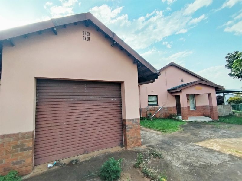 Front exterior view of a single-story house featuring a roller garage door, brick accents, and a covered entrance porch with a concrete driveway.