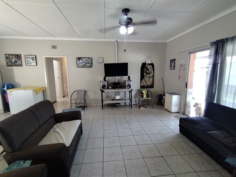 A living room featuring tiled flooring, a ceiling fan, and a sliding glass door providing access to the exterior.