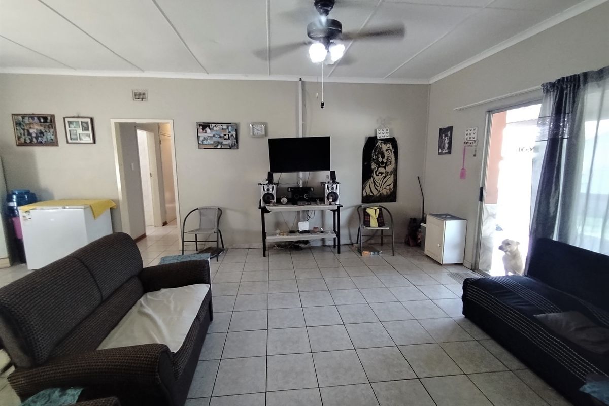 A living room featuring tiled flooring, a ceiling fan, and a sliding glass door providing access to the exterior.