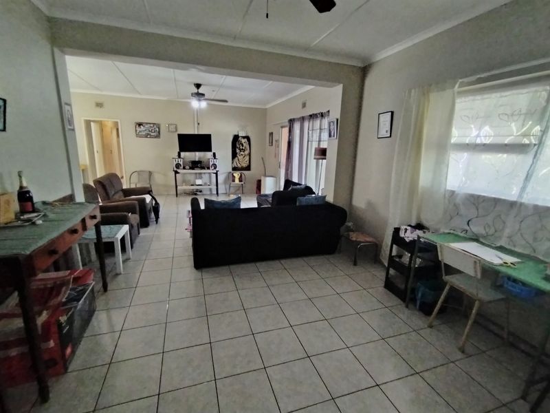 An open-plan living area featuring tiled flooring, a ceiling fan, and access to an outdoor space through a sliding door.