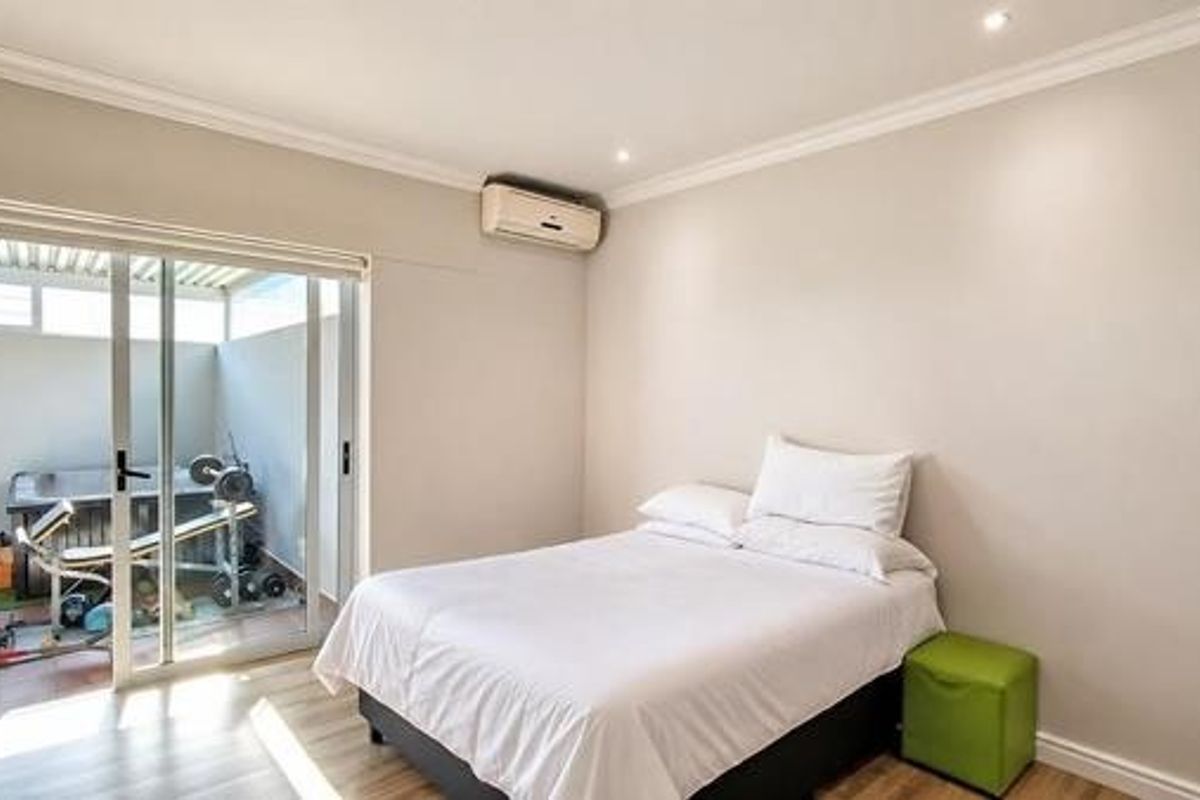 A well-maintained bedroom featuring laminate flooring, recessed lighting, and a sliding glass door providing direct access to an outdoor patio area.
