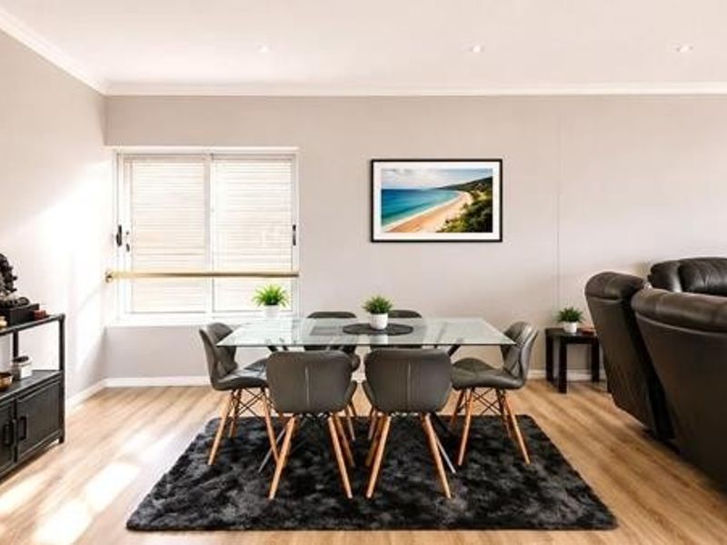 A bright and spacious open-plan living and dining area featuring modern laminate flooring and recessed downlighting.