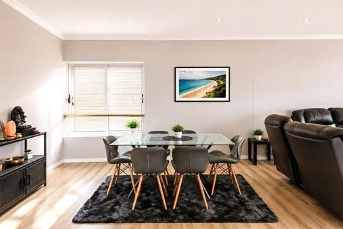 A bright and spacious open-plan living and dining area featuring modern laminate flooring and recessed downlighting.