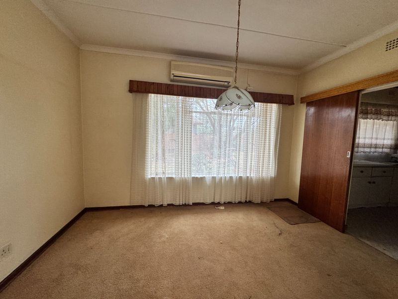 An empty living room featuring carpet flooring, a split-system air conditioner, and a sliding wooden door leading to an adjacent space.