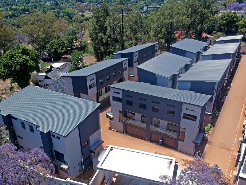 Aerial view of a modern residential townhouse complex featuring contemporary architecture, metal roofing, and paved access roads.