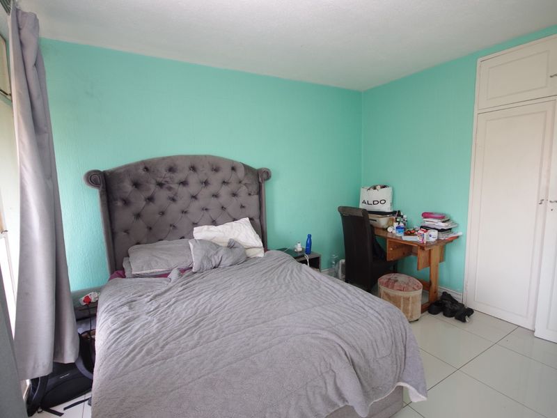 A bedroom featuring tiled flooring and a built-in wardrobe, currently finished with bright teal wall paint.