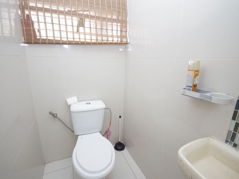A compact bathroom featuring tiled walls and flooring, equipped with a standard toilet and a wall-mounted basin.