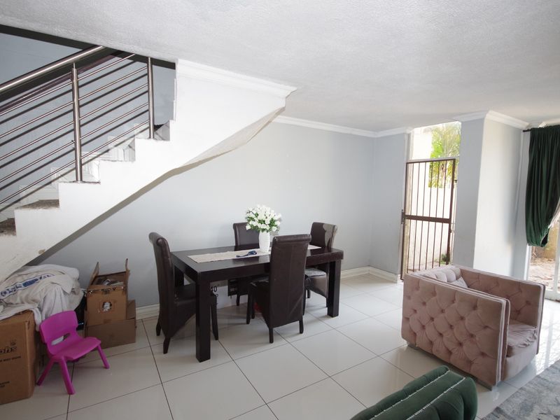Open plan living and dining area featuring tiled flooring, a staircase with a stainless steel balustrade, and direct access to an outdoor area.