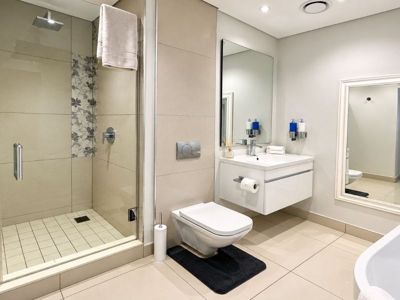 Modern bathroom featuring a walk-in shower, floating vanity, wall-hung toilet, and a sleek freestanding bathtub with neutral tiling throughout.