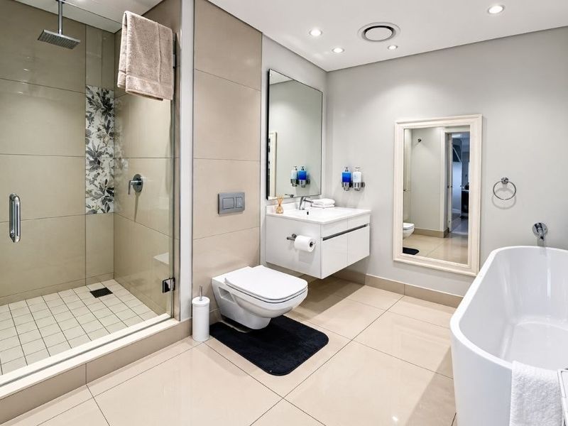 Modern, well-appointed bathroom featuring a spacious walk-in shower, a sleek floating vanity, and a contemporary freestanding bathtub with high-quality tiled finishes.