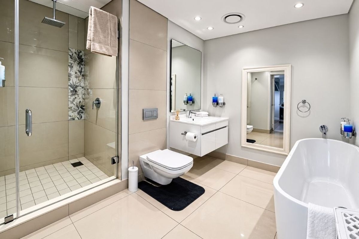 Modern, well-appointed bathroom featuring a spacious walk-in shower, a sleek floating vanity, and a contemporary freestanding bathtub with high-quality tiled finishes.