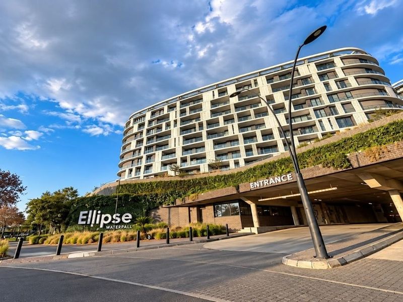 A wide-angle view of the modern Ellipse Waterfall apartment complex, featuring contemporary architecture, landscaped retaining walls, and a secure underground parking entrance.