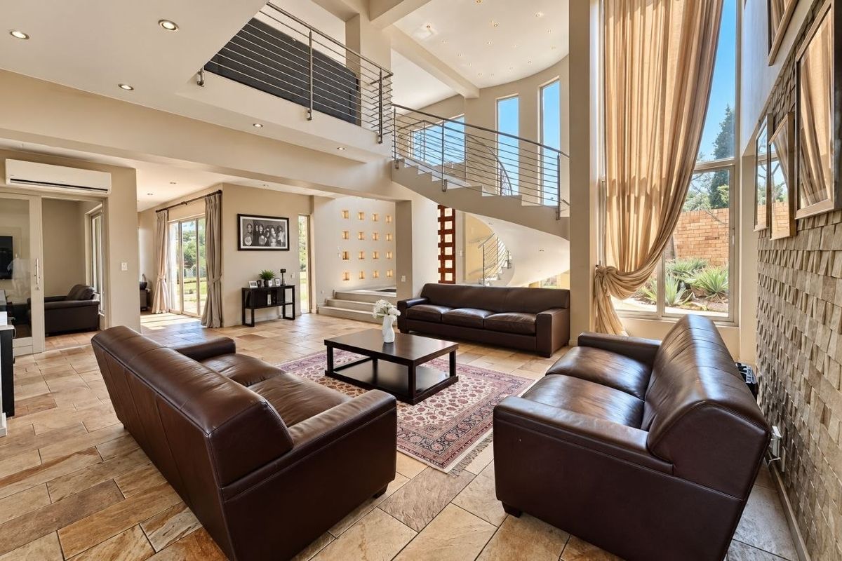 Spacious double-volume living area featuring a striking spiral staircase, stone feature wall, and large windows providing abundant natural light.