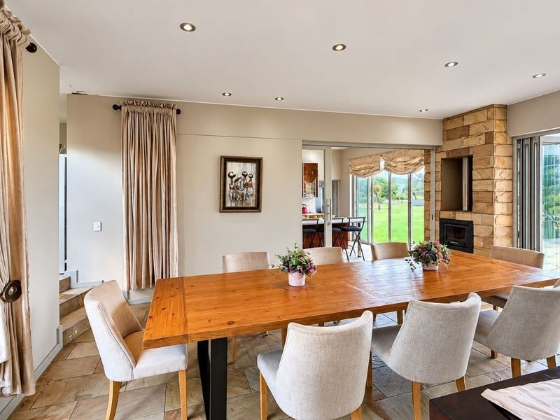 Spacious dining area featuring stone floor tiles, a stone-clad fireplace, and large sliding glass doors providing natural light and access to the outdoor area.