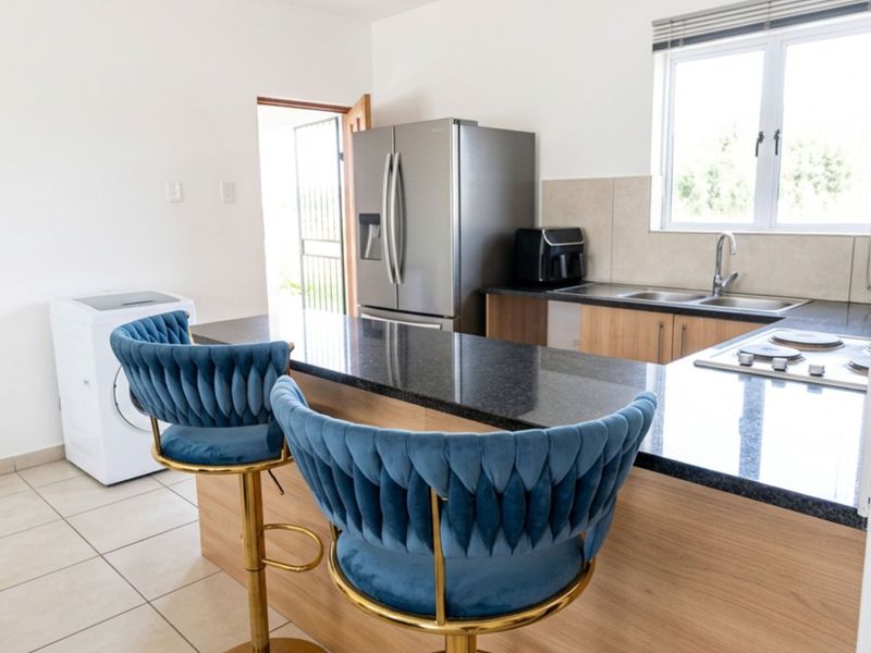 Modern kitchen featuring granite countertops, built-in cabinetry, a gas hob, and a stainless steel sink, with tiled flooring and natural light.