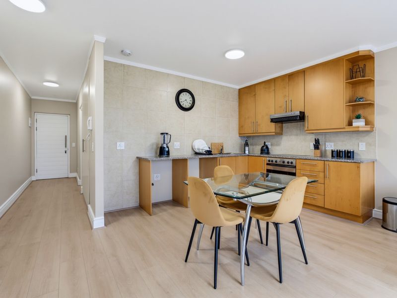 Open-plan kitchen and dining area featuring light wood cabinetry, granite countertops, and modern laminate flooring, creating a functional and bright living space.