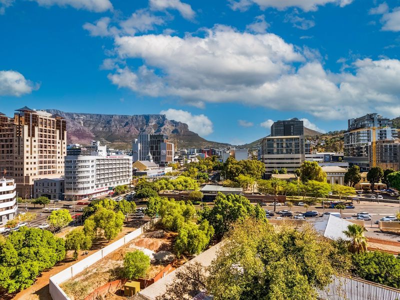 Elevated panoramic view of the city skyline and surrounding mountain range, showcasing the urban landscape and natural scenery.