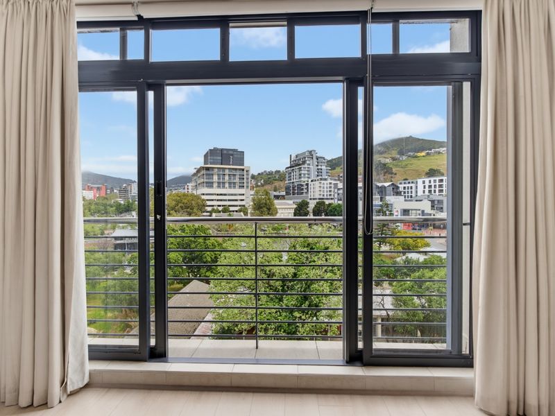 A clear view of the urban landscape and surrounding hills framed by large sliding glass doors and a balcony railing.