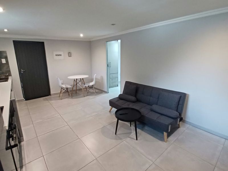 Open-plan living area featuring neutral tiled flooring, recessed downlighting, and direct access to adjacent rooms.