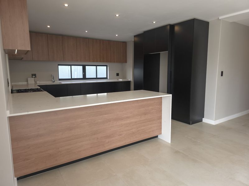 Modern kitchen featuring two-tone cabinetry, stone countertops, a gas hob, and tiled flooring in an open-plan layout.