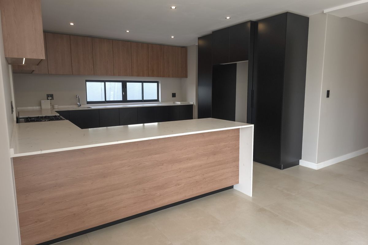 Modern kitchen featuring two-tone cabinetry, stone countertops, a gas hob, and tiled flooring in an open-plan layout.
