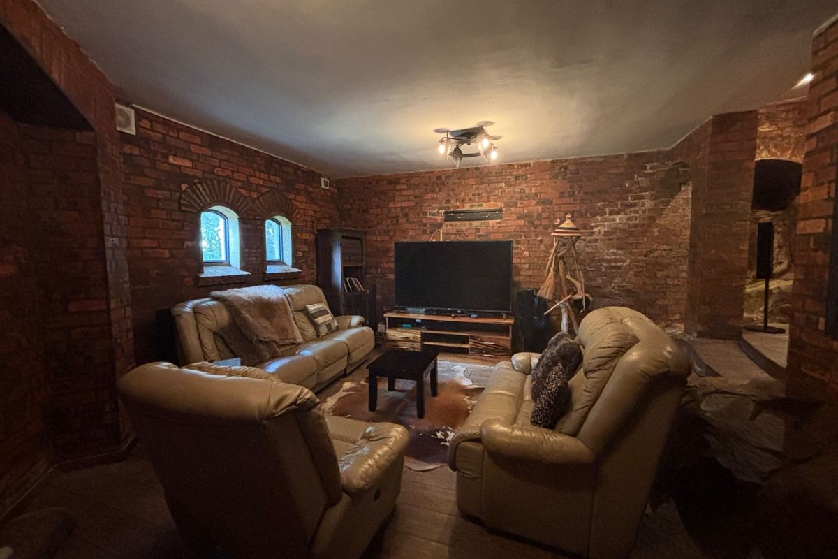A rustic living room featuring exposed brick walls and arched windows, creating a cozy and character-filled atmosphere.