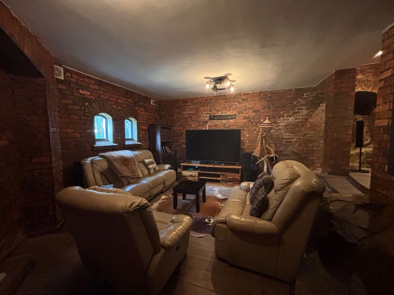 A rustic living room featuring exposed brick walls and arched windows, creating a cozy and character-filled atmosphere.
