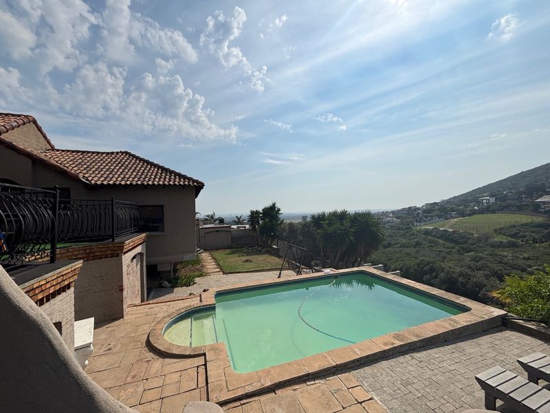 Outdoor pool area featuring a paved patio, wrought iron railings, and scenic hillside views, providing a spacious setting for relaxation and entertainment.