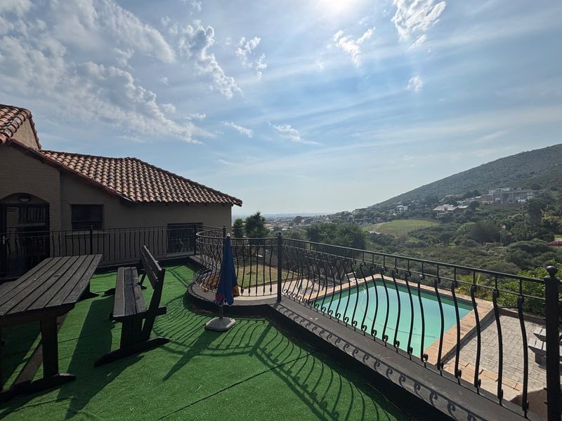 Elevated outdoor terrace featuring a swimming pool, wrought iron safety railings, and expansive hillside views.