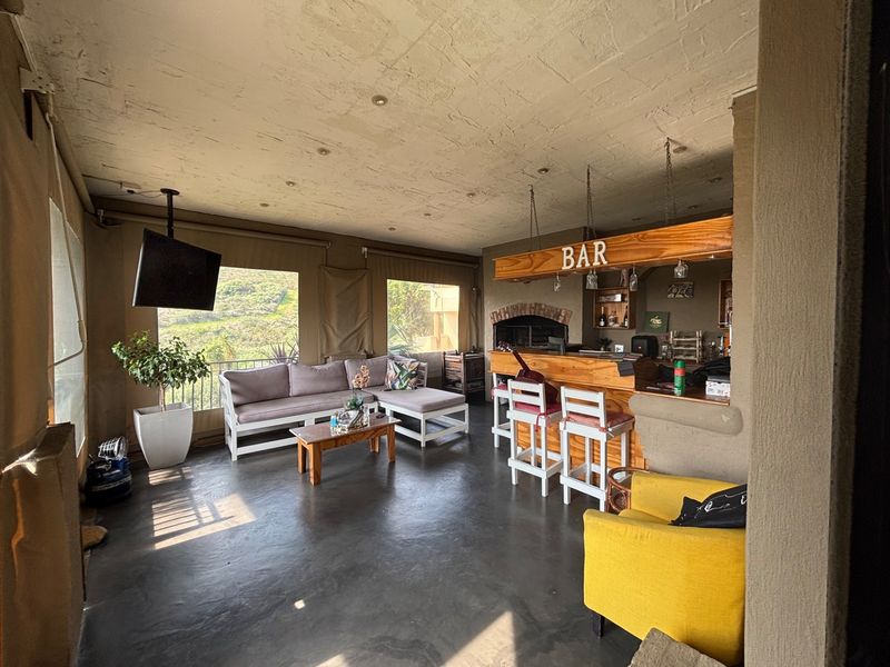 Spacious covered patio featuring a built-in bar and braai area, concrete flooring, and expansive views, ideal for outdoor entertaining.