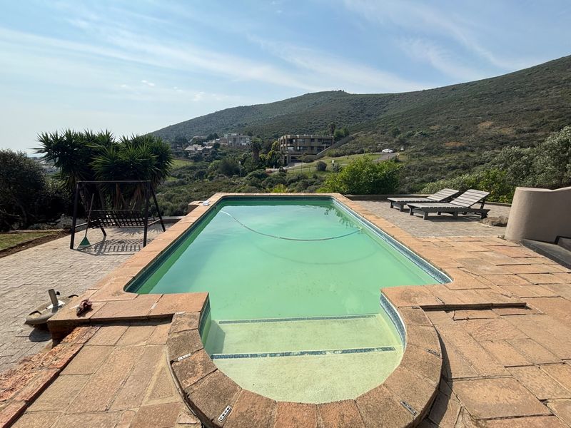 Outdoor swimming pool area featuring a paved deck and scenic hillside views, providing a spacious setting for relaxation and outdoor entertainment.