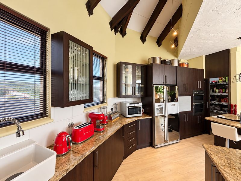 A well-appointed kitchen featuring dark wood cabinetry, granite countertops, a farmhouse sink, and exposed timber ceiling beams, offering a warm and functional cooking space.
