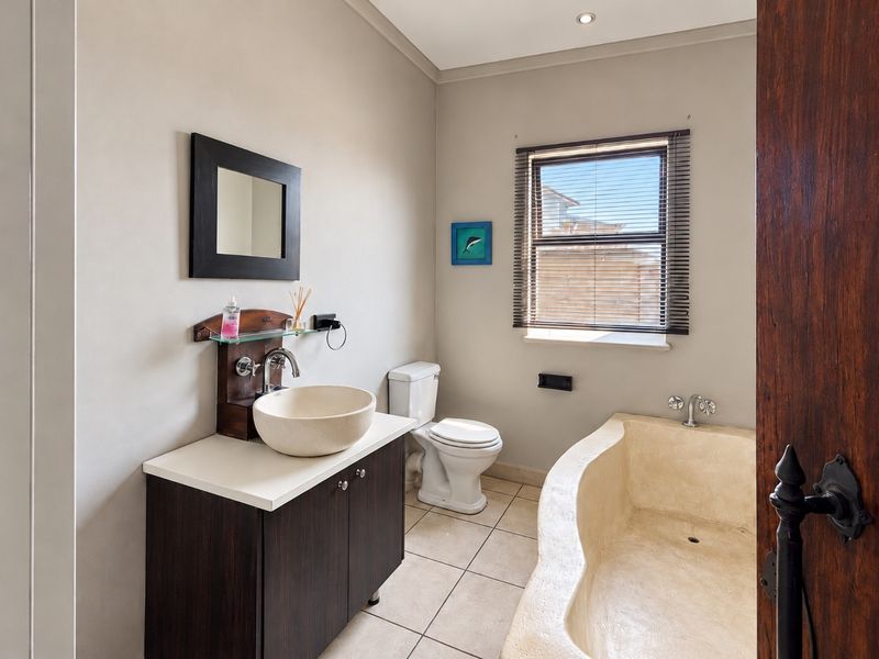 A functional bathroom featuring a vessel sink vanity, a standard toilet, and a built-in bathtub with tiled flooring and neutral wall finishes.