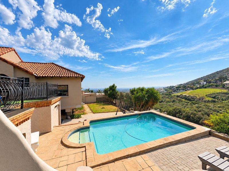 Outdoor pool area featuring a paved deck, swimming pool, and elevated balcony with wrought iron railings, offering expansive scenic views.