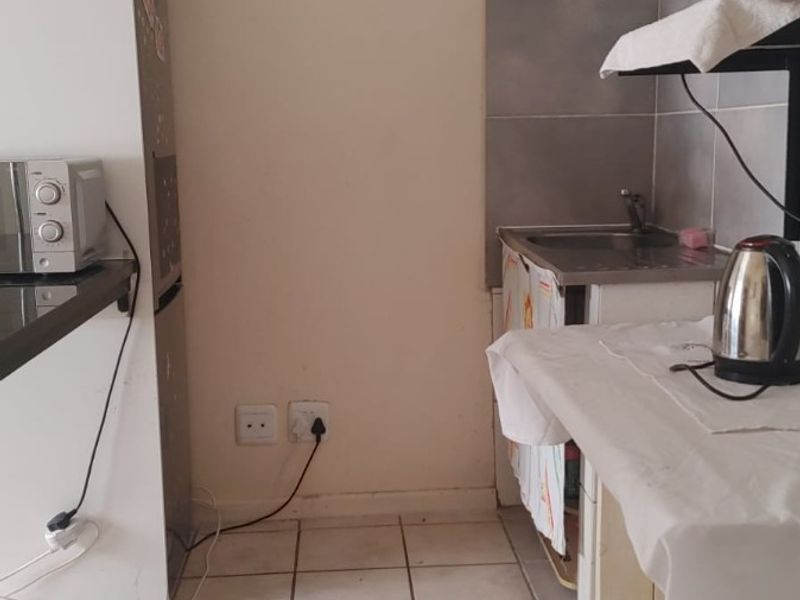 A compact kitchen area featuring tiled flooring, basic cabinetry, and a stainless steel sink, offering potential for modernization and improved layout efficiency.