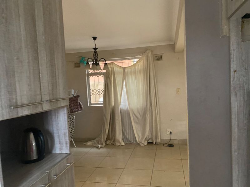A living area featuring tiled flooring and security bars on the window, requiring cosmetic updates to improve the overall condition.