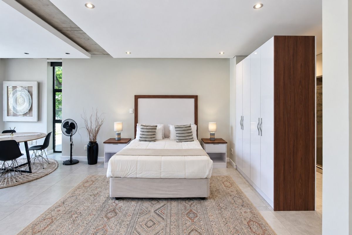 Modern bedroom featuring built-in cupboards, recessed downlighting, and a unique exposed concrete ceiling detail, creating a clean and contemporary living space.